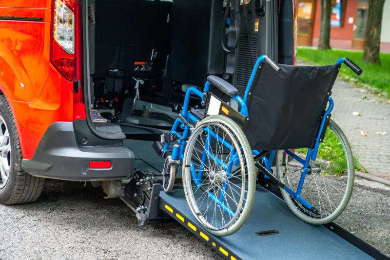 A person using a wheelchair accessing a building with a wheelchair-friendly ramp.